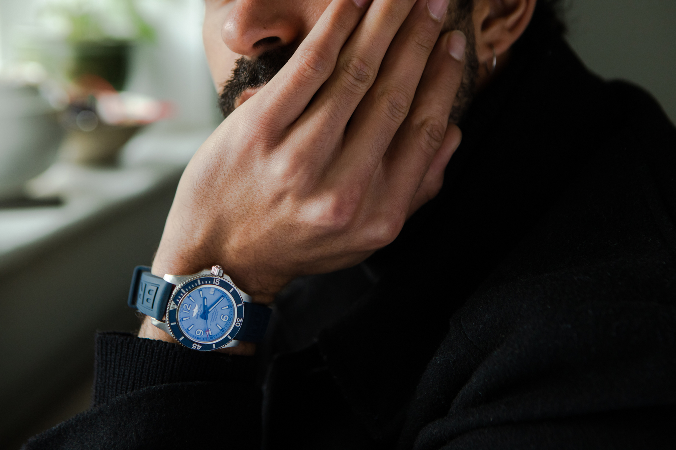 一个人的手腕上戴着一块蓝色百年灵手表，头枕在手上